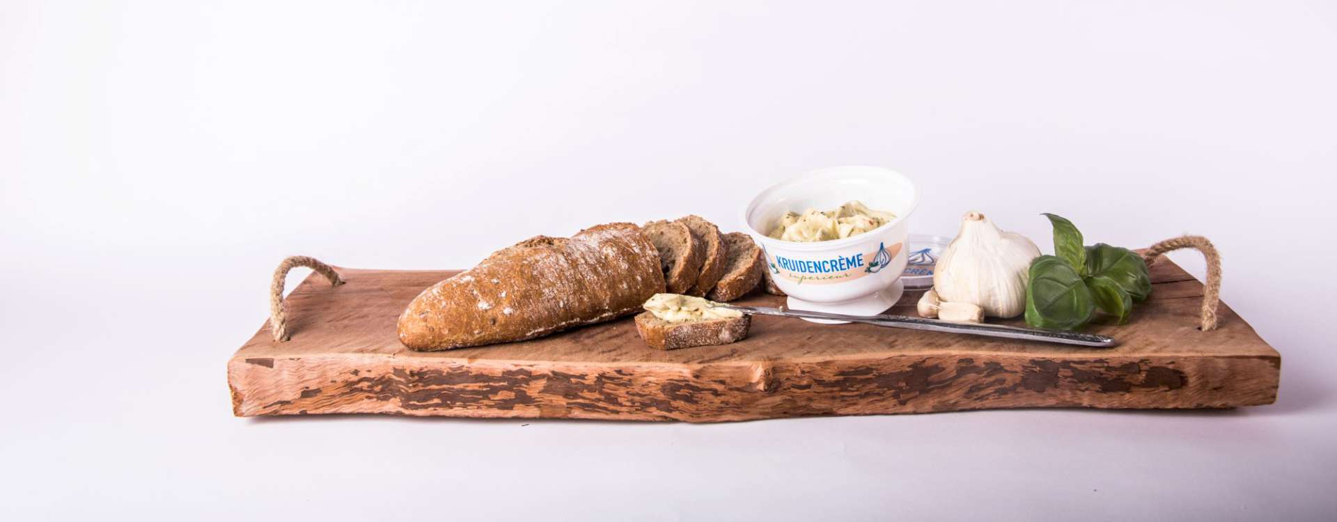 Bedrukt bakje kruidencrème met stokbrood en knoflook op een houten serveerplank